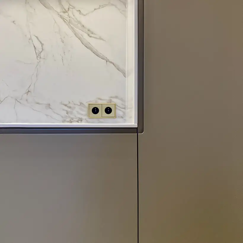 SCHUKO® Steckdosen im Programm LS 990 in Messing Classic, frontal fotografiert im Raumausschnitt, in einer Niesche aus hellem Marmor.