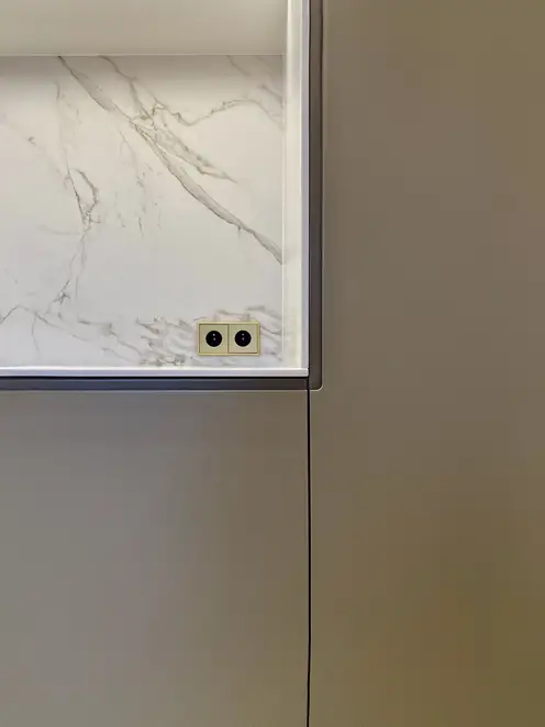 SCHUKO® Steckdosen im Programm LS 990 in Messing Classic, frontal fotografiert im Raumausschnitt, in einer Niesche aus hellem Marmor.